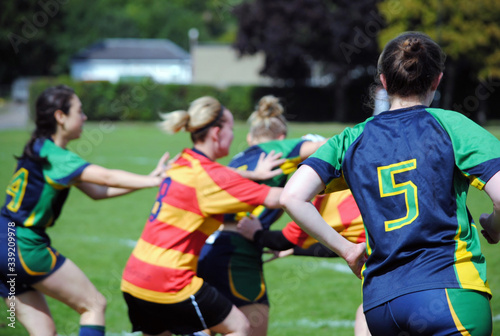 Female sportswomen rugby players struggle for ball