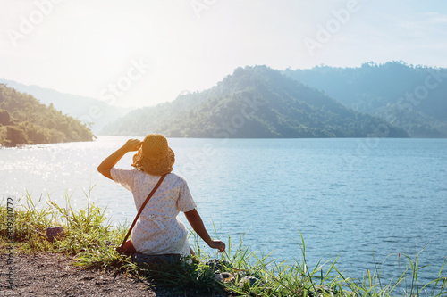 Beautiful young woman looking at view of the mountains landscape at dam in Nakornnayok province, Thailand. Vacation concept photo