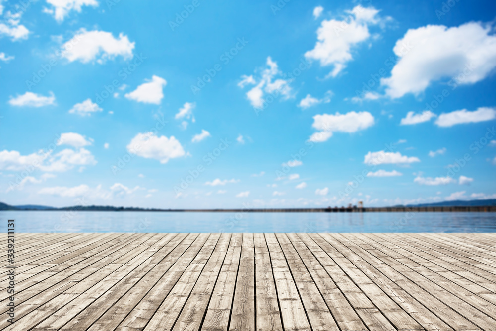 Wood old table against scenic view of the reservoir and blue sky. For your product placement or montage with focus to the table top in the foreground