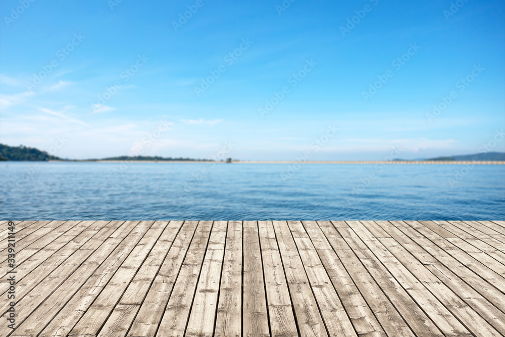 Wood old table against scenic view of the reservoir and blue sky. For your product placement or montage with focus to the table top in the foreground