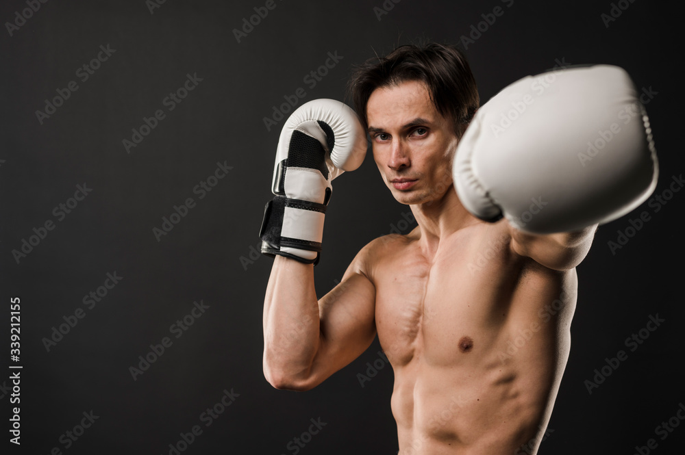 Front view of shirtless muscular man with boxing gloves and copy space Front view of shirtless muscular man with boxing gloves and copy space