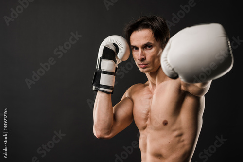 Front view of shirtless muscular man with boxing gloves and copy space © FreepikCompany