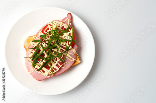 Sandwich of bread for toast, sturgeon, tomatoes, arugula, cheese and mayonnaise on a white plate in the view from the top flat lay, copy space