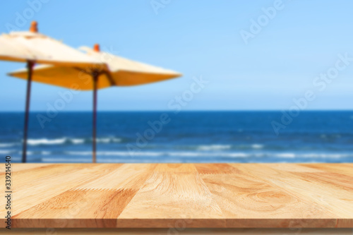Wood table against scenic view of beach landscape and blue sky. For your product placement or montage with focus to the table top in the foreground