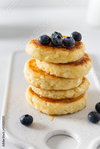 Cottage cheese pancakes with fresh blueberries and honey. Russian syrniki or sirniki, cottage cheese fritters or pancakes served with berries. Restaurant menu, cookbook recipe