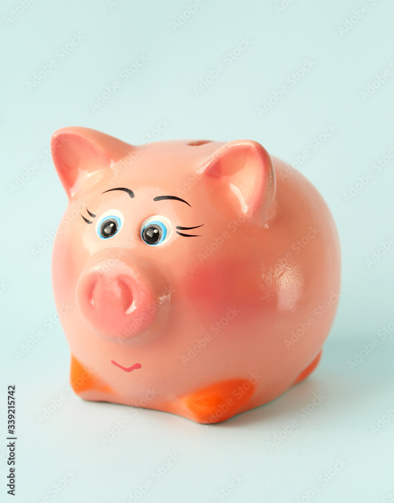 Piggy Bank pink with a cheerful face on a blue background. Home money savings. Selective focus. Accumulation of money