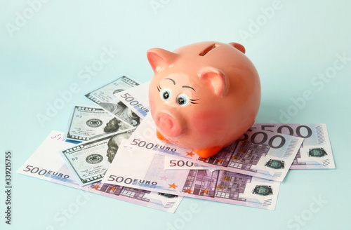 Piggy Bank pink pig made of ceramic is worth 100 dollar and 500 Euro bills. Saving money. Selective focus
