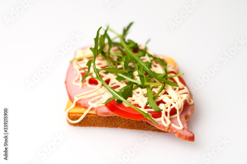A sandwich made of bread for toast, balyk, tomatoes, arugula, cheese and mayonnaise on a white background view from the side and from the top