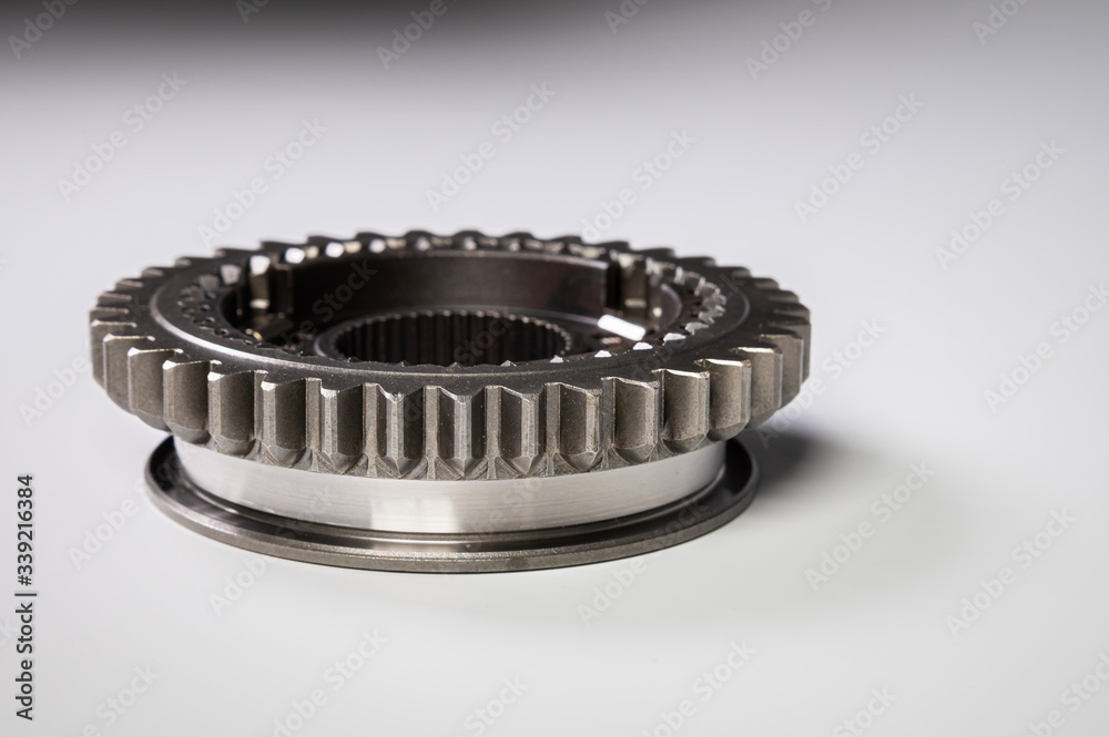 New parts on a gray background. Gears of gear shifting torque transmission. Conceptually mechanical background. Shiny gear box gear teeth New parts on a gray background. Gears of gear shifting torque transmission. Conceptually mechanical background. Shiny gear box gear teeth