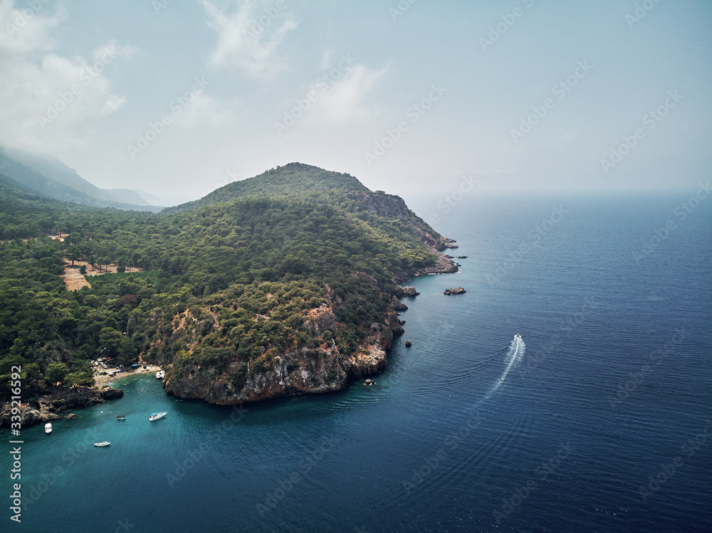 turkey, aerial drone perspective of deep blue and turquoise water of the mediterranean sea. Moody weather with many green trees. nice sandy white yellow beach