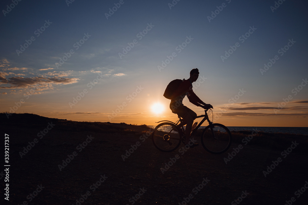 Fototapeta premium Silhouette of cyclist in motion at beautiful sunset.