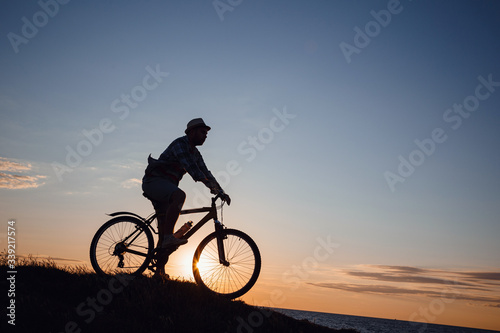 silhouette of a hipster man on a bicycle on sunset background