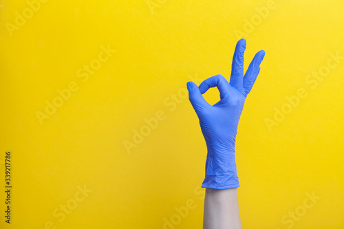 Doctor hand in medical lilac surgical rubber glove shows gesture okay photo