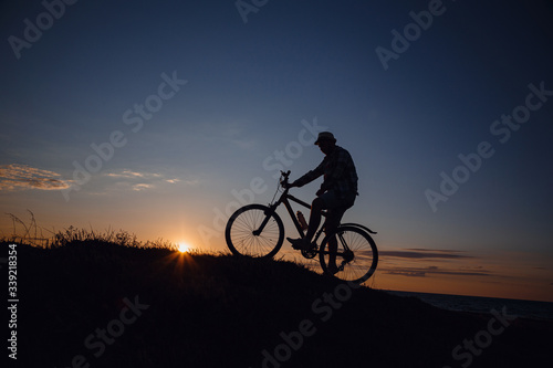 silhouette of a hipster man on a bicycle on sunset background