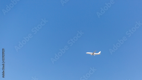 The plane flies in the clear blue sky. Cloudless blue sky over which the plane flies.