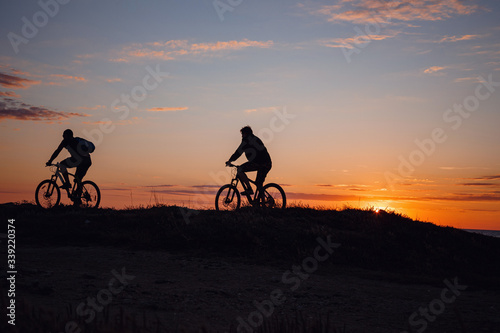 two friends on bikes enjoy a beautiful sunset