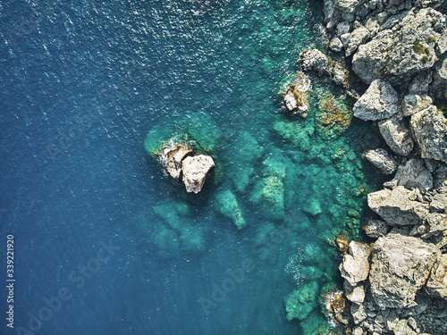 Sharp stones and rocks in the turquoise, blue sea. Drone aerial shot from above with white stone coast. Turkey