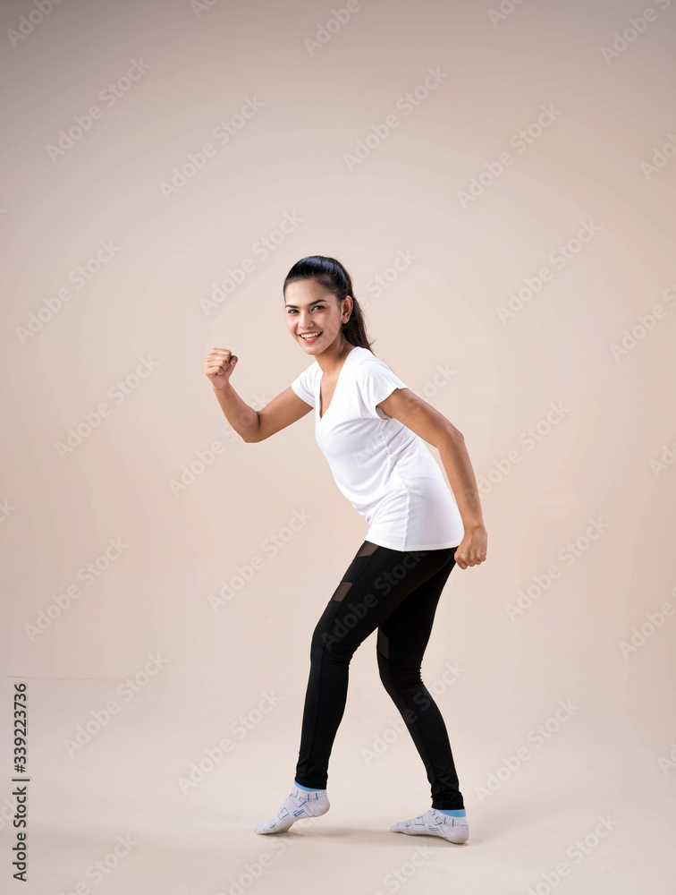 Young lady standing feet apart,twisted a little,raise fist up and down beside her body,moving for dance workout,with happy feeling Young lady standing feet apart,twisted a little,raise fist up and down beside her body,moving for dance workout,with happy feeling