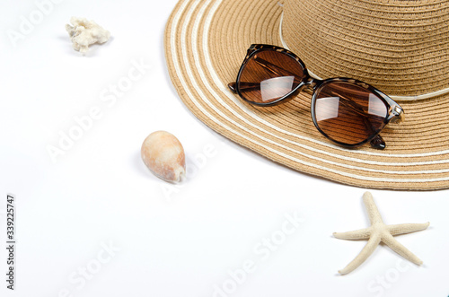 Summer straw hat, sunglasses, shells, starfish on white background.