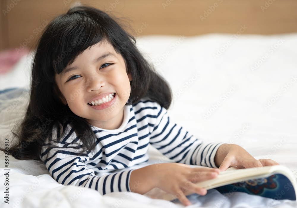 Little cute child girl lying on the bed and reading a book. education concept. Little cute child girl lying on the bed and reading a book. education concept.
