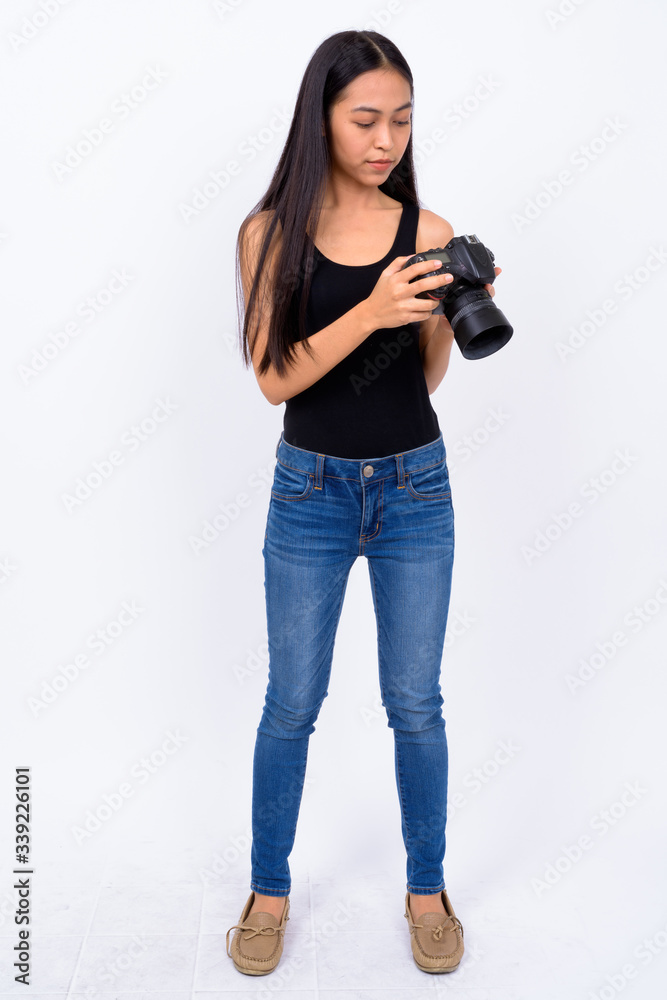 Full body shot of young Asian woman using camera Full body shot of young Asian woman using camera