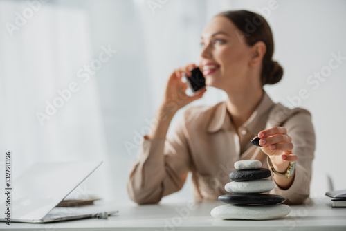 Photography selective focus of businesswoman talking on smartphone at workplace with zen sto