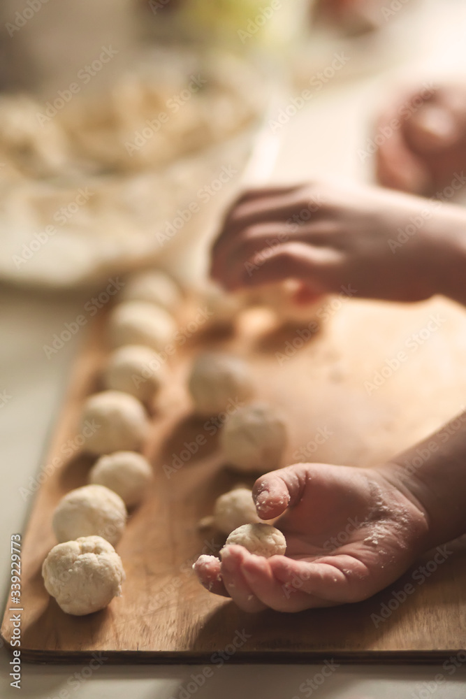 Children making a cottage cheese balls Russian syrniki in the home kitchen.