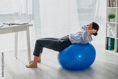 young smiling businesswoman doing abs on fitness balls in office