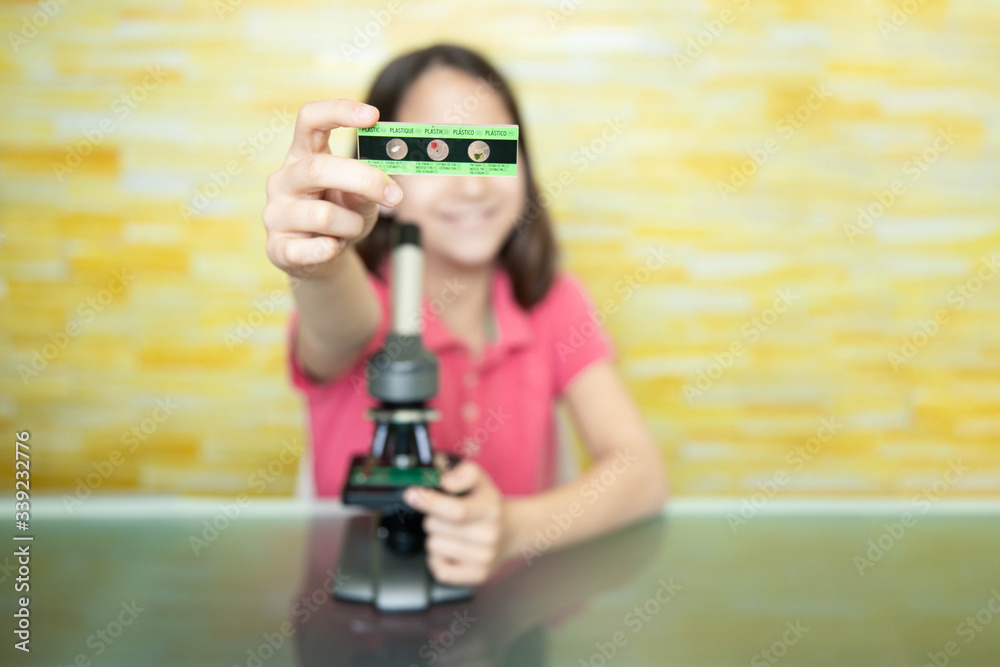 Smiling girl showing a microscope slide at home