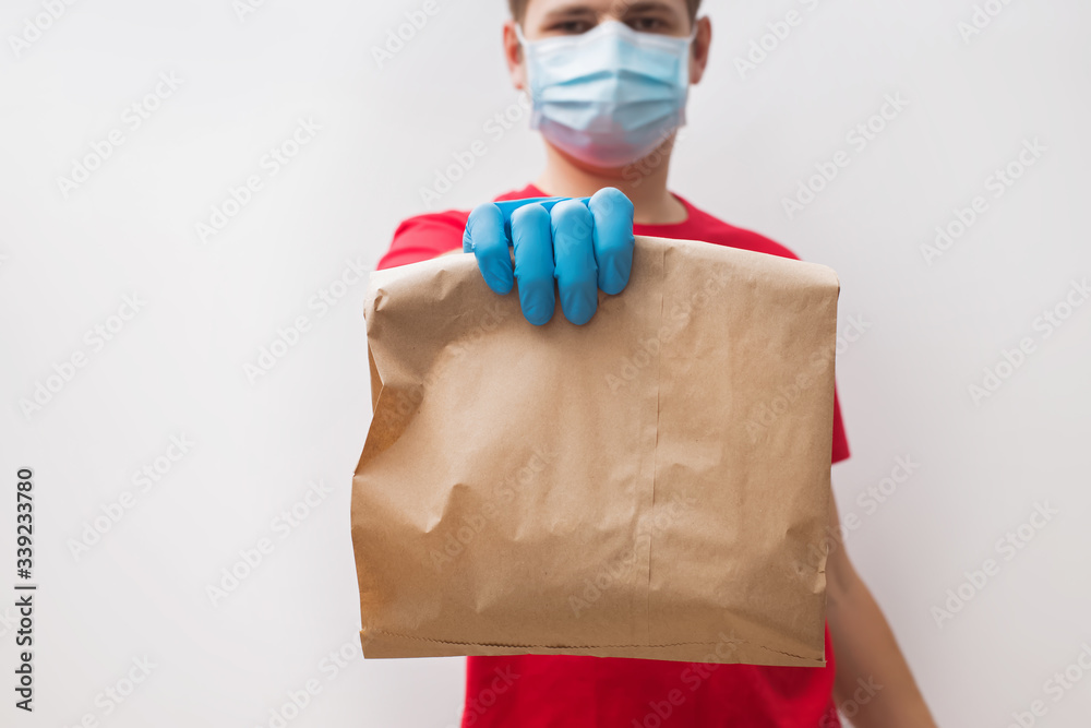 Courier wearing protective gloves and mask holding paper bag with food Courier wearing protective gloves and mask holding paper bag with food