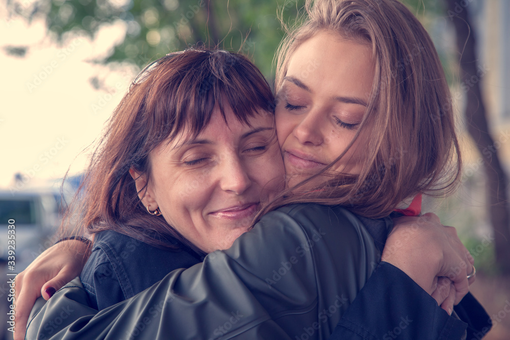 Fototapeta premium April 25, International Daughter's Day, Mother's Day, happy family, mother and daughter cuddle tenderly, natural feelings