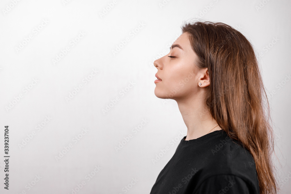 beautiful young woman on a white background stands in profile in a black shirt. copyspace. isolated beautiful young woman on a white background stands in profile in a black shirt. copyspace. isolated