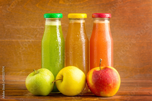 apple fresh juice from green, red and yellow apples on wooden background