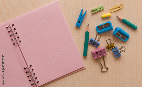 
pink notebook paperclip pencils and on the table