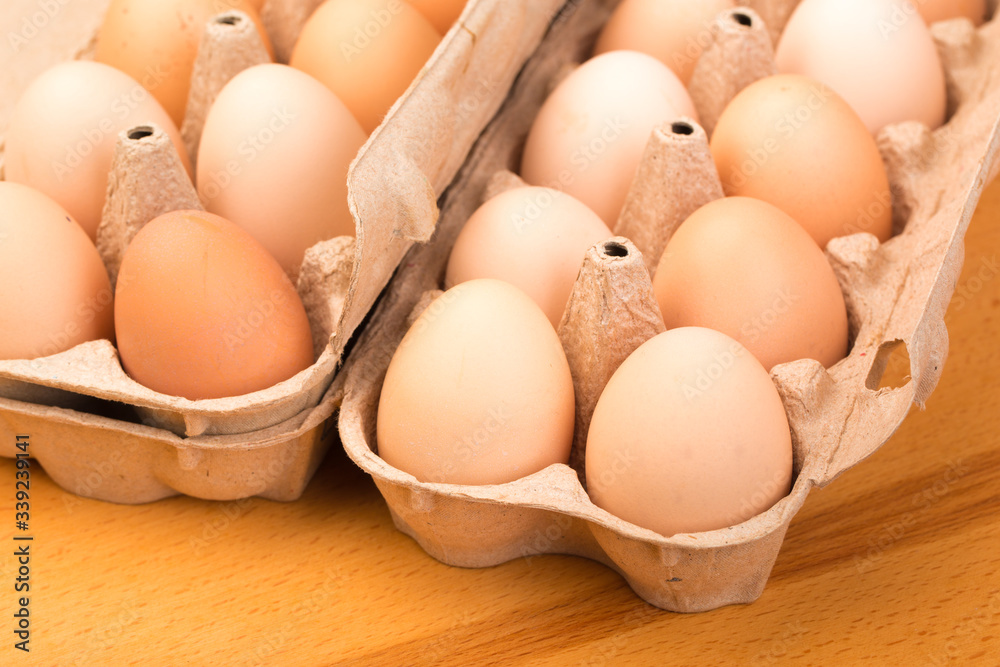 brown chicken eggs in an open cardboard box with eggs on a wooden table. Natural healthy food. brown chicken eggs in an open cardboard box with eggs on a wooden table. Natural healthy food.
