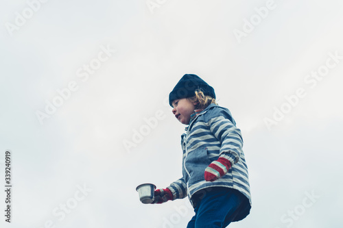 Preschooler carrying cup of tea outdoors in winter
