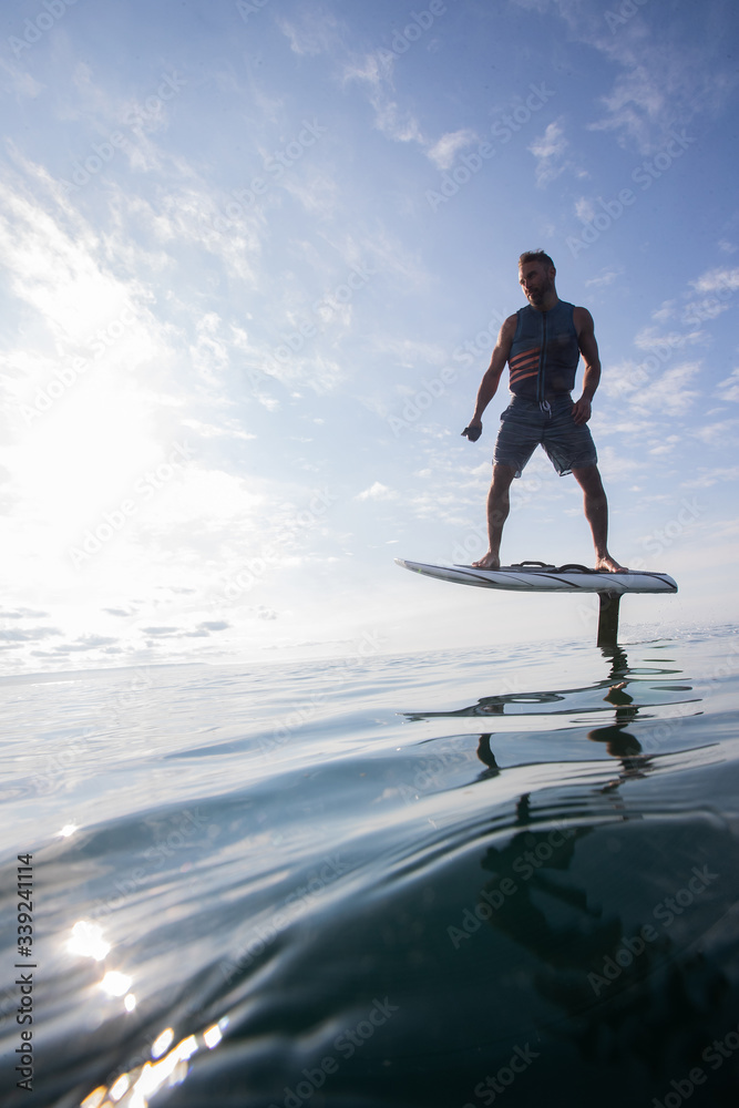 Man riding an electric hydrofoil foil board on a lake with a life jacket