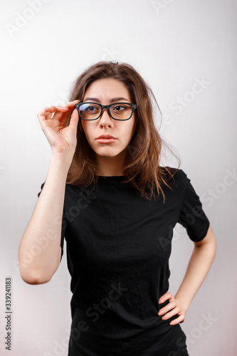 beautiful young woman on a white background looks away with glasses and a black shirt. copyspace