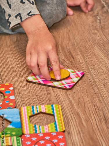 Kid's hands with Montesori pazzls close-up. Montesori wooden game for the development of children. Child development retardation. photo