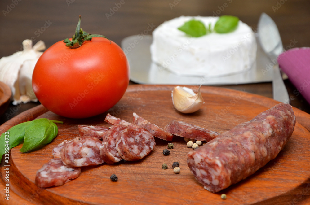 sausage with pepper and vegetables on a wooden board and cheese in the background sausage with pepper and vegetables on a wooden board and cheese in the background