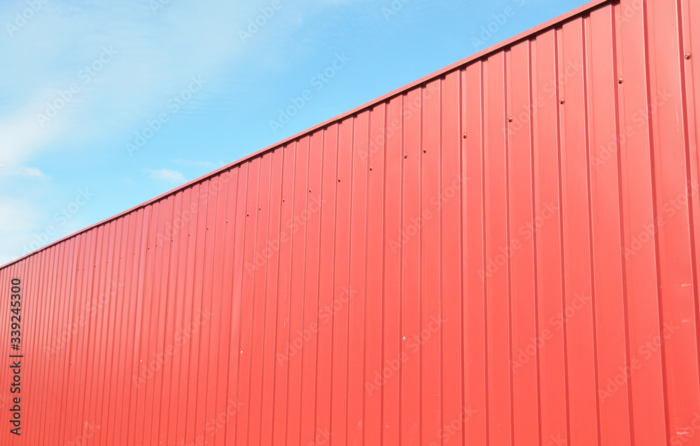 Metal fence design: a red corrugated steel fence panels agains blue sky. Metal fence design: a red corrugated steel fence panels agains blue sky.