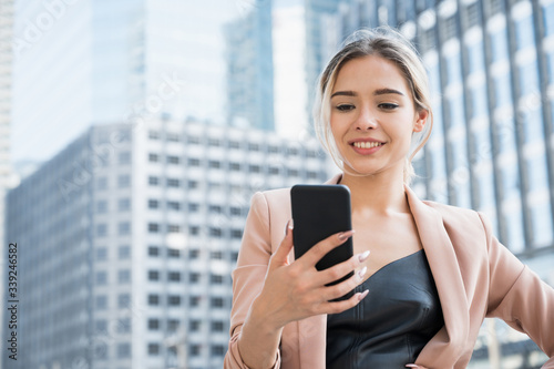 Portrait of smiling pretty young business woman using phone on office background. Free Download Portrait of smiling pretty young business woman using phone on office background. - GFXLoad