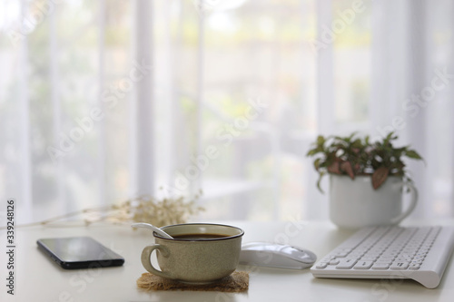 Interior house modern decor with smartphone coffee and white keaboard and mouse and plants pot with see through curtain  