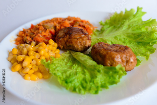 Fried chicken cutlet with potato slices served with tomato cherry and corn salad. Traditional belorussian food - roasted minced meat and potato
