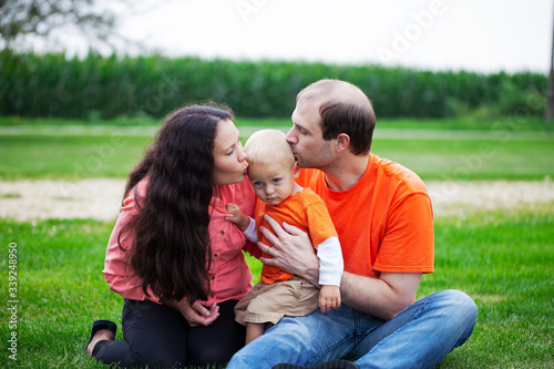 Portrait of happy parents kissing their baby son outdoors