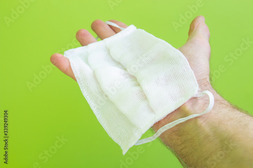 hand holds surgical mask, medical protective mask isolated on green background. Covid-19 virus protection concept