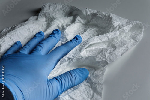 Mano con guanto in lattice pulisce una superfice bianca con un panno photo