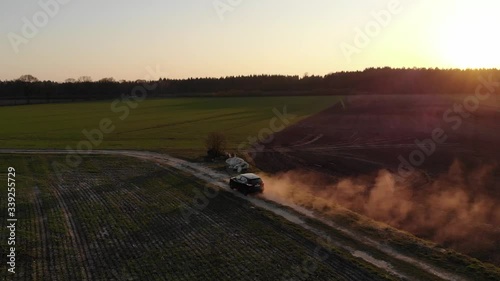 Schwarzes Auto SUV auf Feldweg voller Staub beim Sonnenuntergang während der Corona Pandemie