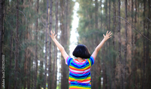 A girl life hand up feel happy at outdoor travel in Pine forest