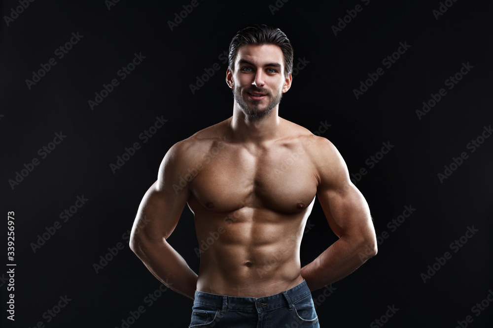 Young athletic man with a naked torso isolated on a black background.